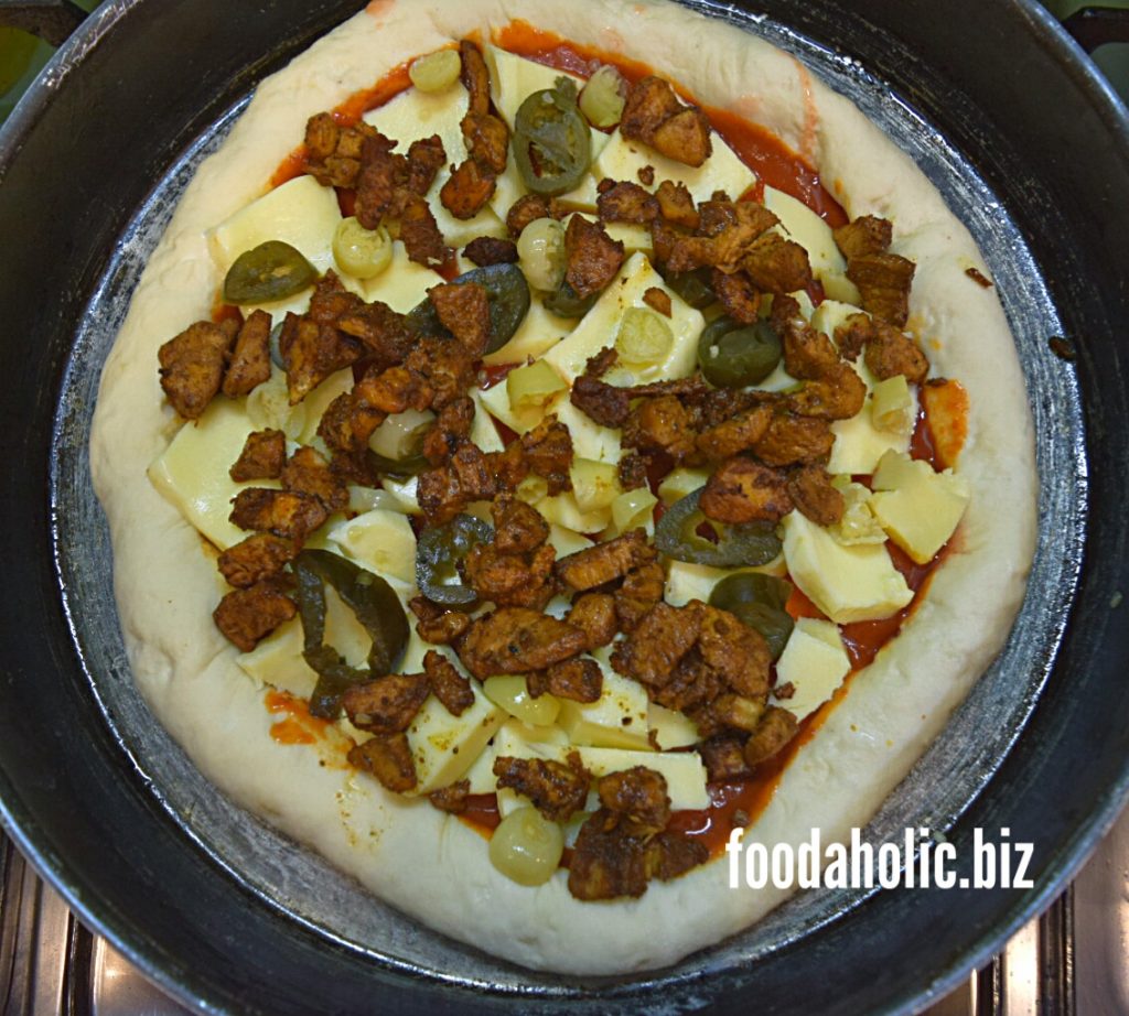Homemade Pizza Dough with toppings and sauce in a deep pan for backing.